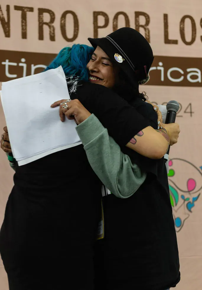 Dos personas se abrazan en el escenario de EXA CDMX 2024