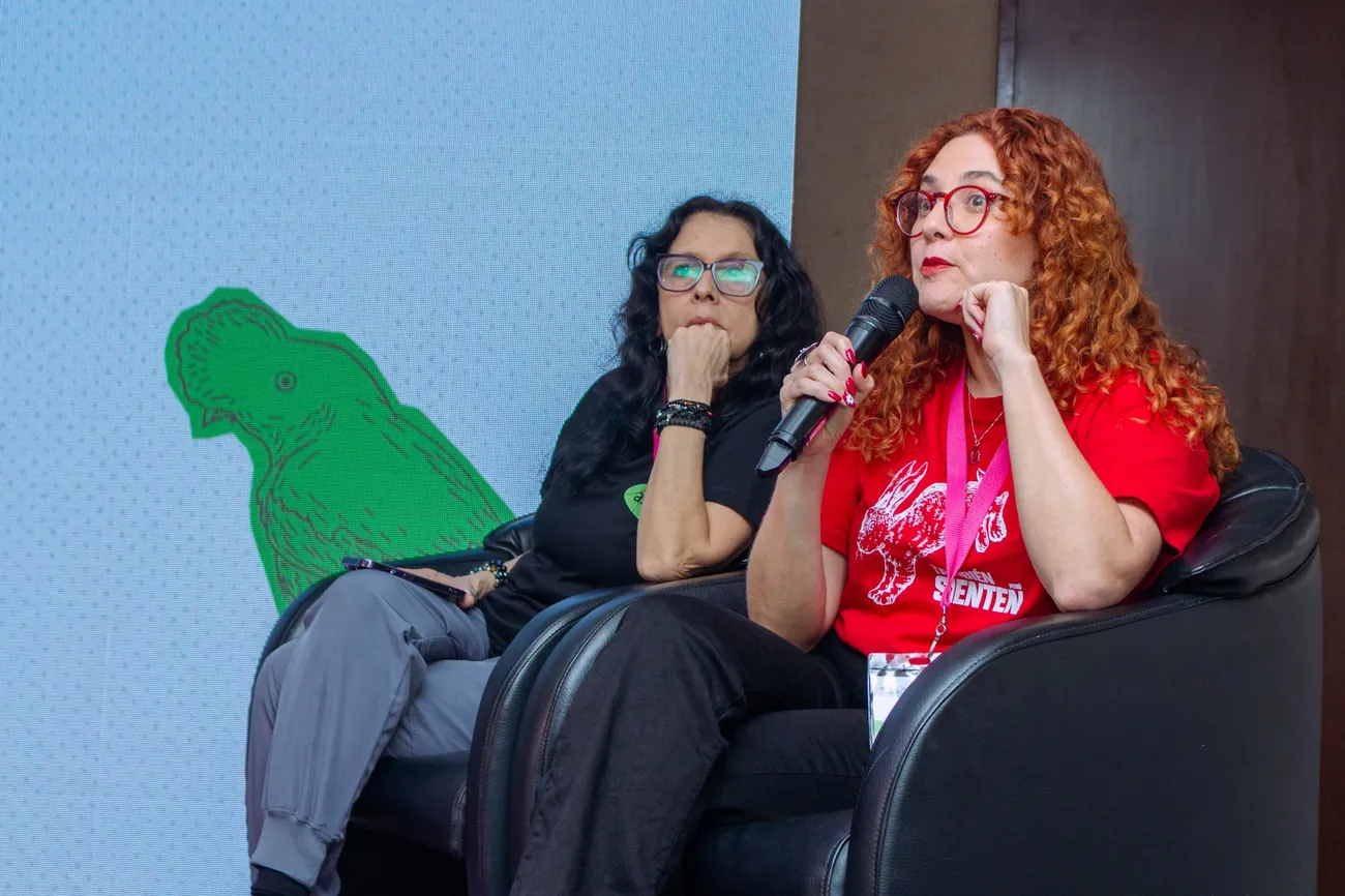 Dos ponentes en un panel, una de ellas habla con micrófono