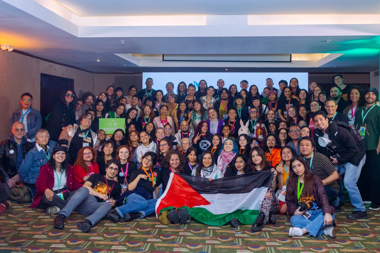 Foto grupal de participantes de EXA con una bandera de Palestina