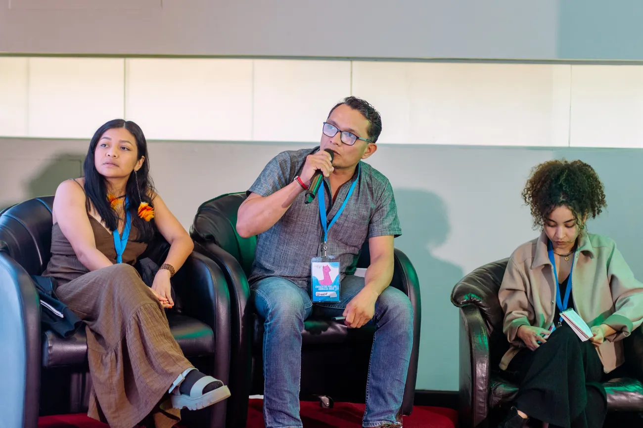 Panel de tres personas; el ponente del centro habla con micrófono