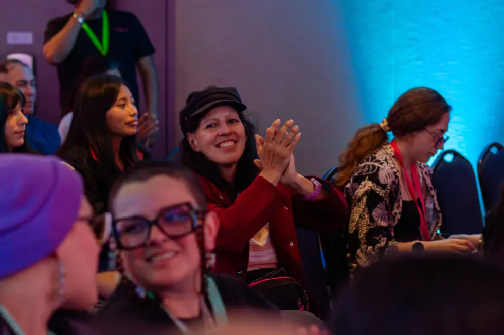 Participante aplaude sonriente entre el público