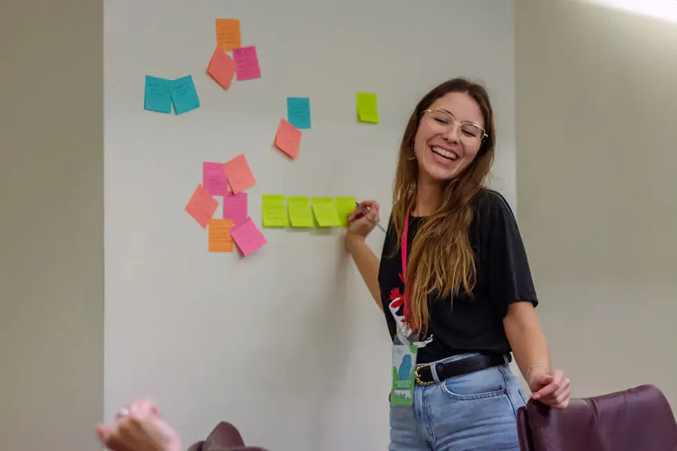 Participante pega notas de colores en la pared durante un taller