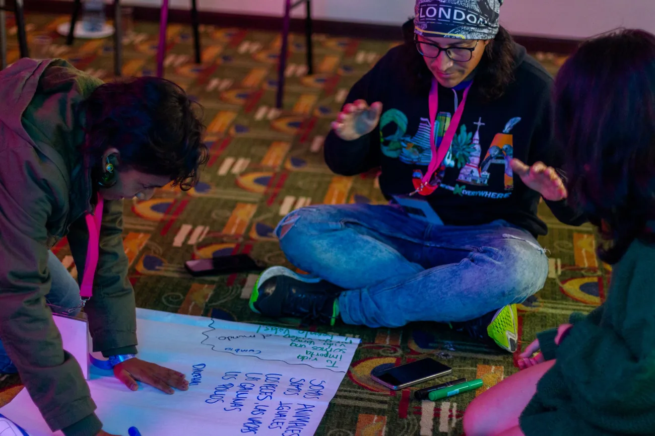 Participantes escriben en un papelógrafo sentadas en el piso durante un taller